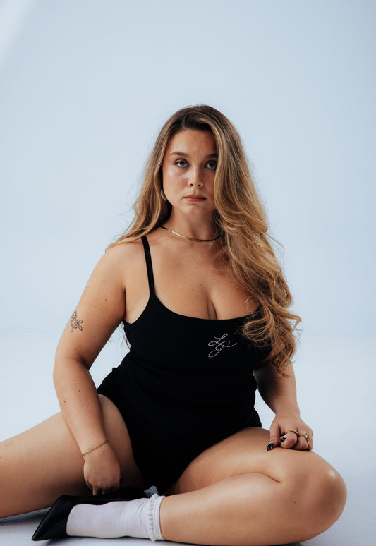 Woman wearing a black tank top with a logo on a light blue background